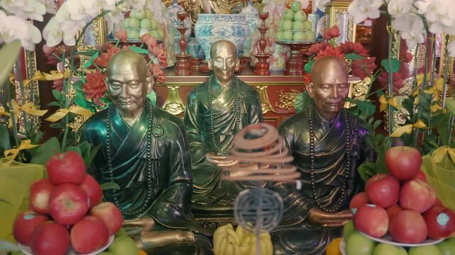 A traditional altar of intricately decorated with golden dragons and Chinese patterns Buddhist Temple with a central golden-robed seated bearded deity and smaller white attendant statues 