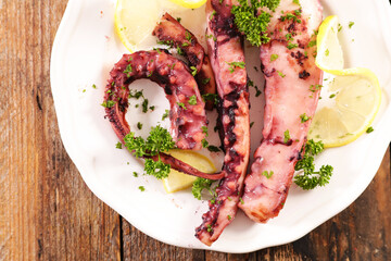 Grilled Octopus Tentacles with Lemon and Parsley Served on White Plate © M.studio