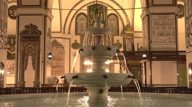 Turkey mosque fountain pool reflects warm night lights inside a quiet sacred interior.