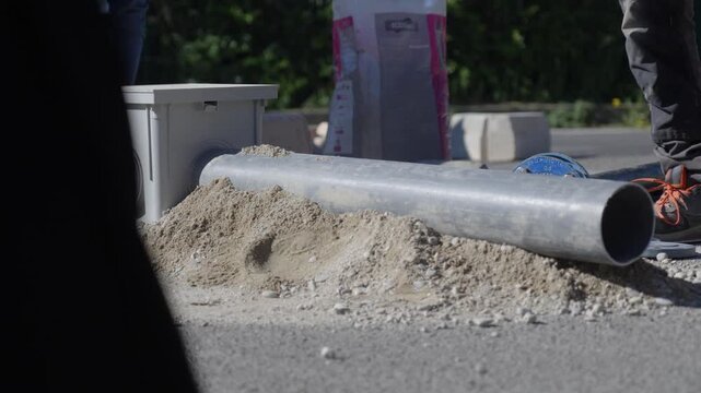 Underground utilities construction with plastic pipes and a junction box on a sandy trench during public works in Bordeaux, France.