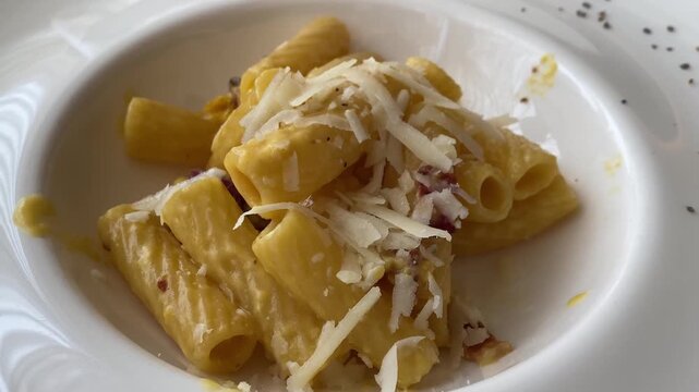 Italian maccheroni carbonara pasta dish topped with pecorino romano cheese.