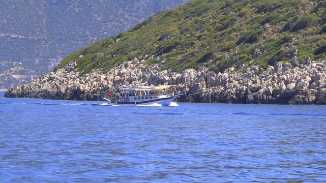 Turkish excursion boat cruises coastal waters near islands and peninsulas in bright daylight.