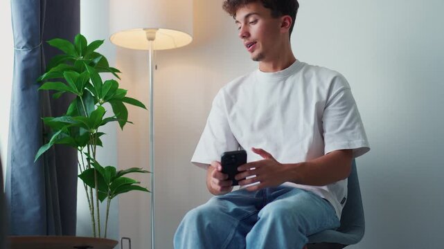Young man using a smartphone and turning on the lamp to relax