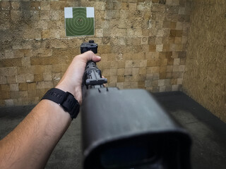First person view aiming a tactical rifle with laser sight at a target in an indoor shooting range © Dmitri