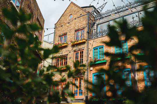 Colorful brick courtyard with vibrant windows and greenery in London