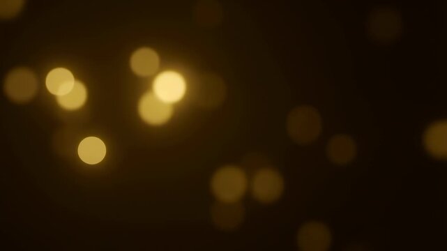 Intentionally blurred golden bokeh light circles drift across a dark abstract background. Holiday greetings, luxury advertising, and event promotions.