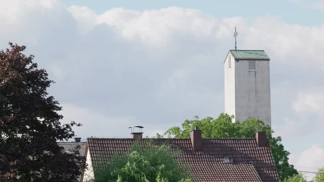 Church tower above village rooftops slow motion the wind shakes the leaves on the trees