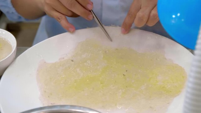 The manual cleaning process of edible bird's nests (yanwo), a delicacy made from the solidified saliva of swiftlets. Worker uses tweezers to carefully remove feathers, debris