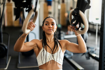 Focused young woman training with gymnastic rings