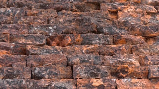 The weathered, coarse texture of an ancient reddish-orange brick or laterite stone wall of Po Nagar Temple Tower in Nha Trang, Vietnam. Closeup. Shot in motion