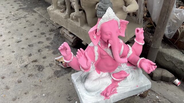 Handcrafted bright pink Lord Ganesha idol placed outdoors in an artisan workshop before Ganesh Chaturthi.