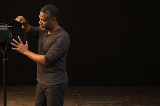 Stage lighting technician adjusting barn doors on a theatre lantern