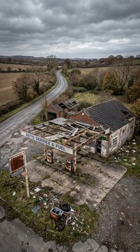 Dilapidated gas station stands abandoned beside a winding rural road. Decaying infrastructure symbolizes the shift toward electric vehicle adoption.
