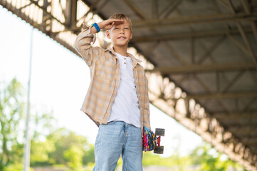 Fair-haired boy of school age with a skateboard looking confident © zinkevych