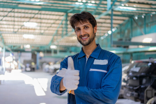 Hispanic mechanic giving thumbs up in auto repair shop
