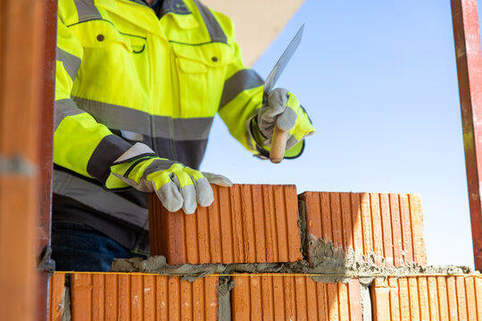 Construction worker laying brick with trowel on site