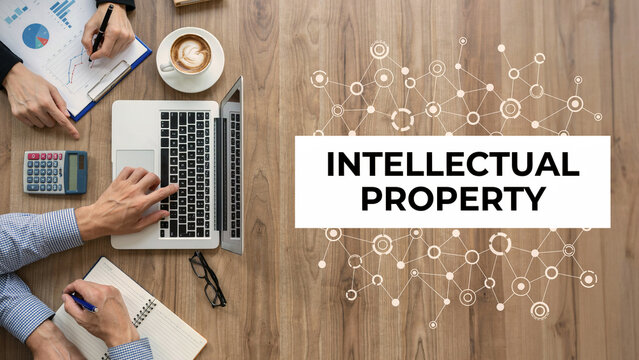 Intellectual property concept with business people analyzing data and technology network on wooden desk