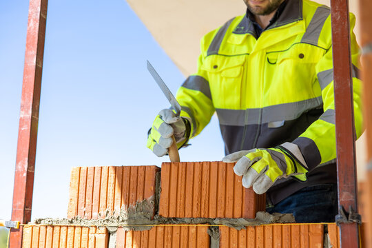 Construction worker applying mortar with trowel on brick