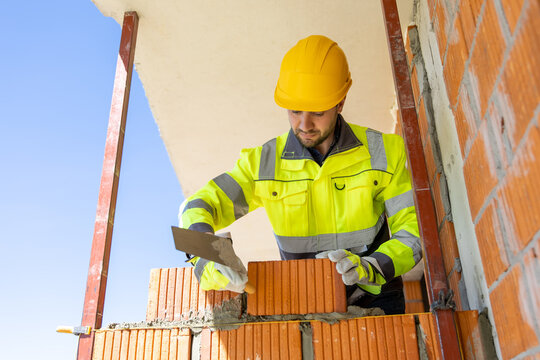 Construction worker holding trowel near brick wall