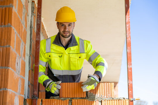 Construction worker holding trowel and brick outdoors