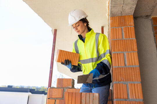 Female construction worker holding brick and trowel