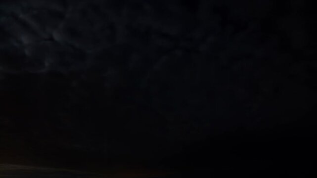 Dark storm clouds drift across a near-black night sky as horizon light fades. Weather broadcast, film and television atmosphere, and suspense title sequence.