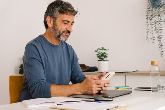 Man using smartphone app at desk while working at home