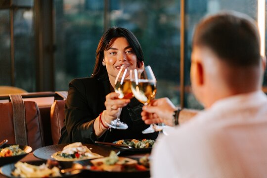 Woman and man clinking wine glasses while dining together during a romantic evening in a restaurant