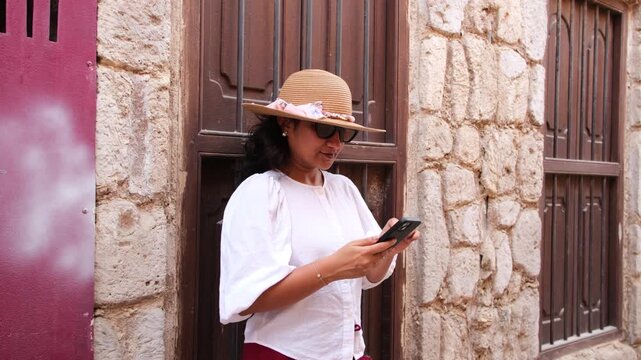 Female traveler using smartphone while exploring Al Fahidi Historical Neighbourhood and traditional architecture in Old Dubai