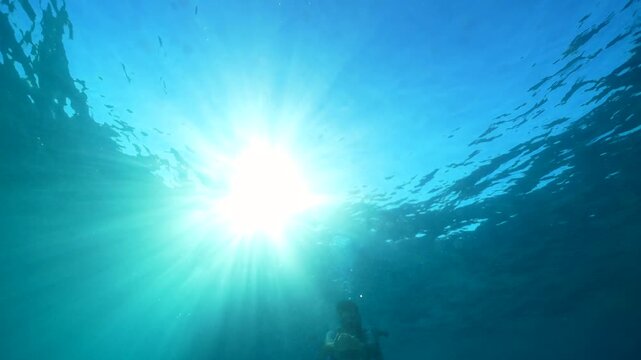 Man snorkeling and diving underwater in the ocean waving at camera, enjoying summer vacations and adventure trip