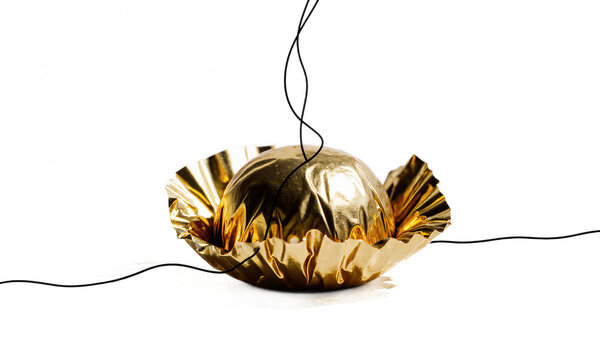 Chocolate truffle gold isolated candy on a transparent background with thin wires wrapped around for an artistic display