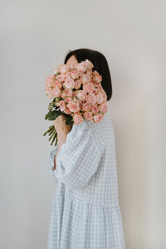 Soft portrait of brunette with pink roses against cream studio backdrop