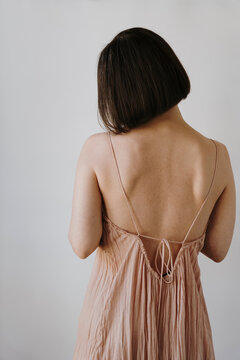 Woman Wearing Pastel Pink Dress. Minimalist fashion portrait with elegant pose and neutral background