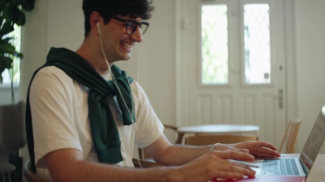 Man laughing on on video call in indoor workspace, illustrating remote work, freelance communication, online meetings, and digital business activity.
