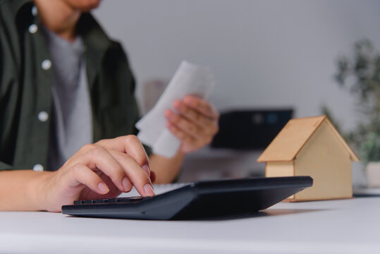 Business Person Writing Documents with Calculator at Desk