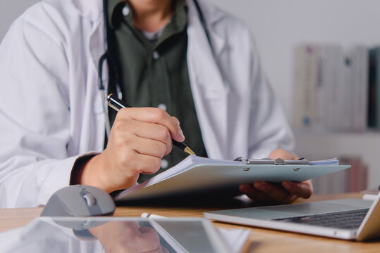 Doctor Writing Medical Notes at Office Desk