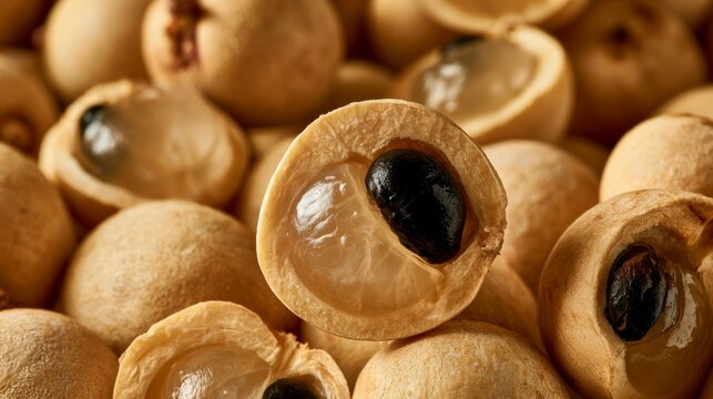 Close-up of fresh longan fruits, one cut open revealing juicy flesh and seed