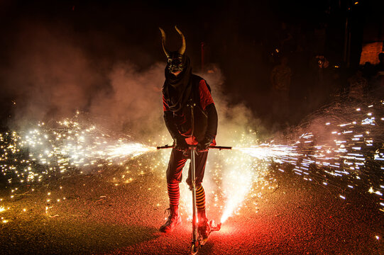 Correfoc devil mask rider creating sparks on scooter