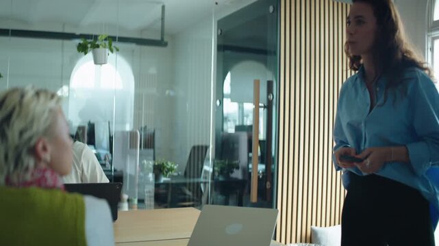 Coworkers shape business ideas in a conference room while a woman leads discussion around the table, highlighting collaboration, brainstorming, communication, and group planning.