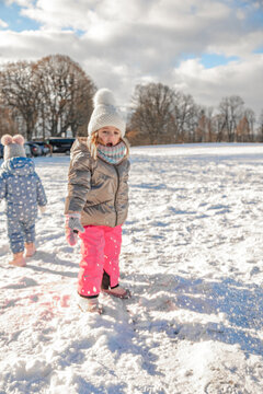 Little girl walking and playing on snowy path in countryside field during bright sunny winter day, children active outdoor leisure and winter walks concept, happy kids running in snow