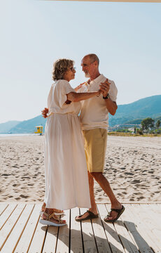Senior couple dancing on beach enjoying retirement