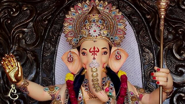 Ganesha idol showing blessing hand mudra gold crown and marigold garlands during Ganesh Chaturthi festival India.