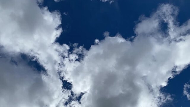 Time lapse of white and gray clouds moving across a blue sky, revealing and obscuring patches of blue as cloud cover changes.