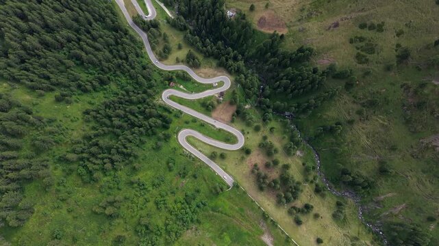 Aerial view showcasing the dramatic curves of Passo Giau mountain pass, framed by the striking Ra Gusela summit in the Italian Alps