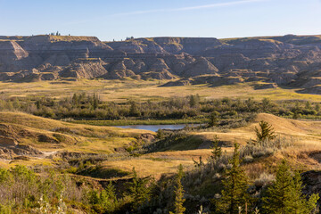 Obraz premium Layered Alberta badlands and pond in warm sunlight