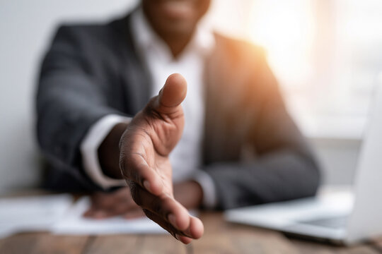 A first person perspective of a business handshake offer with shallow depth of field.