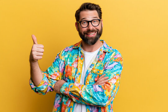 A portrait of a smiling man with glasses, a beard, and a multicolored shirt over a white shirt, set against a solid vivid background.