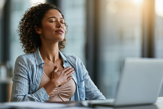 An employee sitting in a bright, modern office taking a purposeful, 1-minute meditation break. Eyes closed, one hand on their chest.
