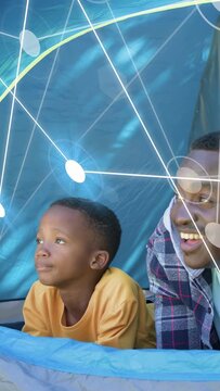 Vertical video: Dad and son in blue tent, boy glancing up, starting tech overlay, pointing skyward