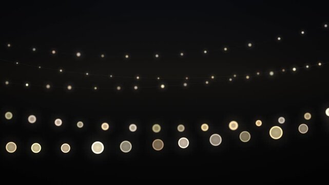 Strands of heavily defocused warm white string lights hanging and twinkling in the dark, seamless 4K loop